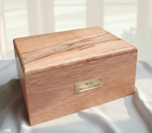 A large wooden pet cremation urn with a light finish, featuring a secure compartment in the base and an engraved name plate on the front.