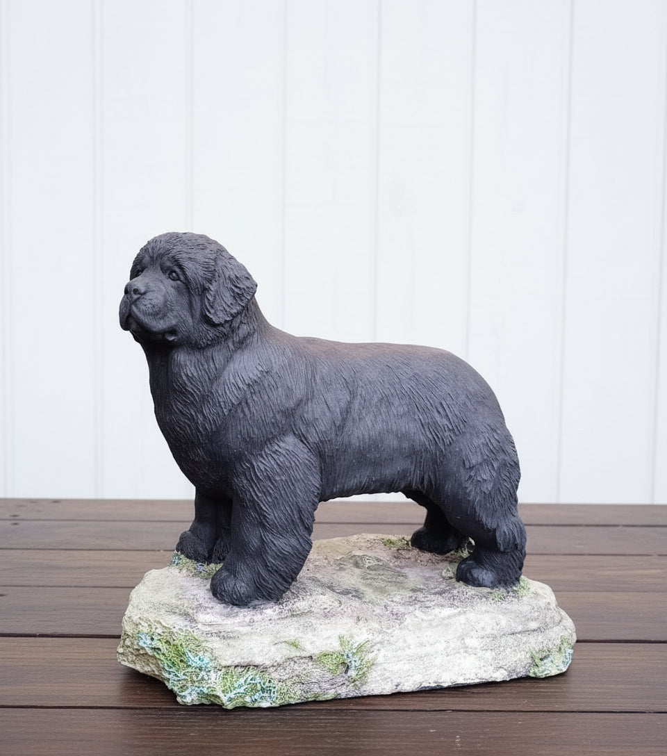 Statue of a black dog on a stone base against a white paneled wall.