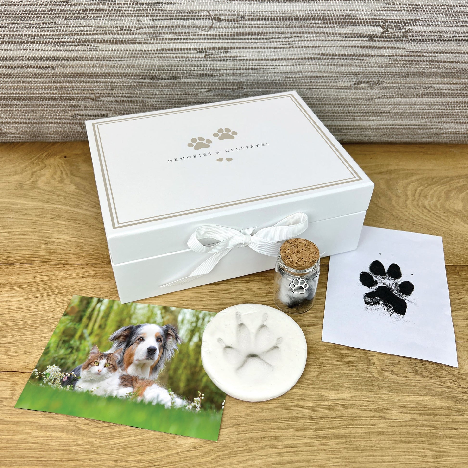 Memorial kit for pets with a photo of a dog, paw print mold, and other items on a wooden surface.